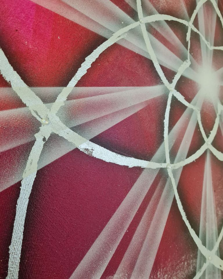 Weiß lackierte Linien und Strahlen bilden ein geometrisches Muster auf einem roten Untergrund, das an eine Venusblume erinnert.